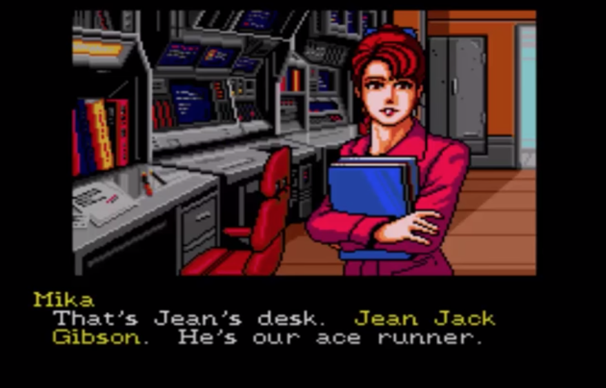 Junker HQ receptionist Mika talks to the player in Snatcher. Screenshot text: "That's Jean's desk. Jean Jack Gibson. He's our ace runner."