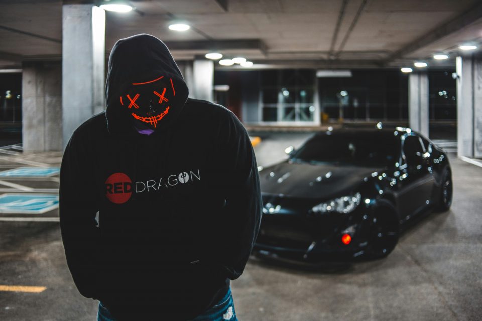 Stock image of masked man standing in the vicinity of a car