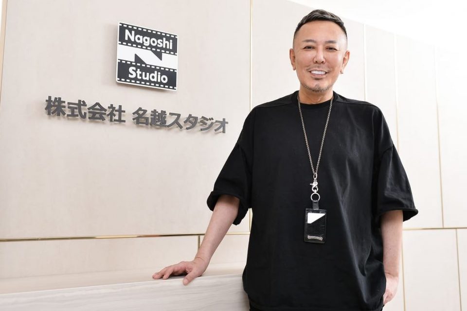 Toshihiro Nagoshi against the logo of Nagoshi Studio